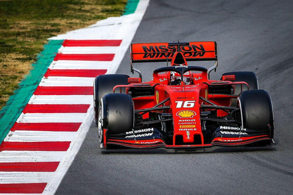 Charles Leclerc racing Ferrari on Formula 1 track near curb showing speed and precision Wallpaper