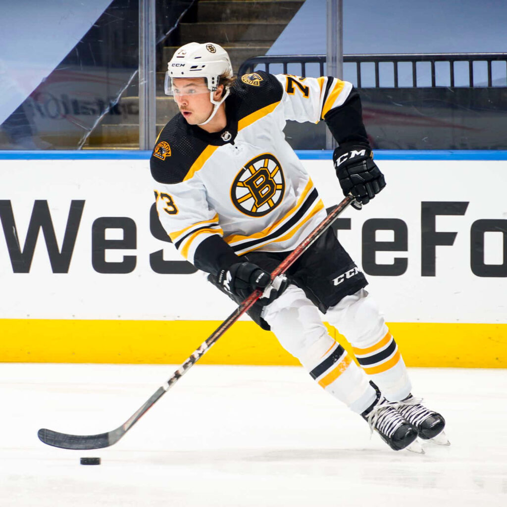 Boston Bruins Charles McAvoy skating in white gold uniform dynamic hockey wallpaper background
