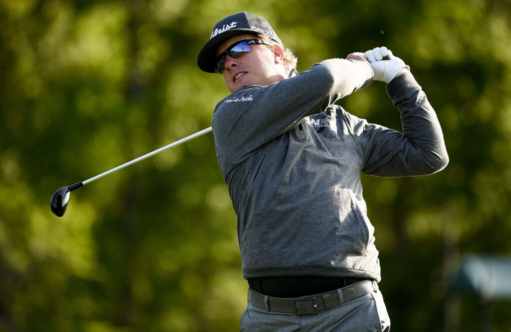 Charley Hoffman mid swing on lush green golf course wearing gray jacket and black cap focused Wallpaper