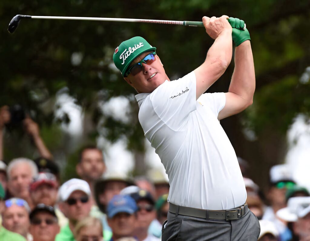 Charley Hoffman mid-swing on vibrant golf course wearing white shirt green gloves green cap Wallpaper