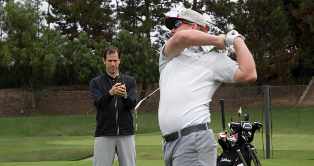 Charley Hoffman powerful golf swing on lush green course white shirt and cap golf coach background Wallpaper