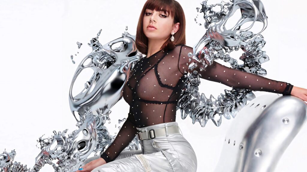 Charli XCX in sheer gem-studded top and metallic pants with futuristic silver liquid forms background Wallpaper