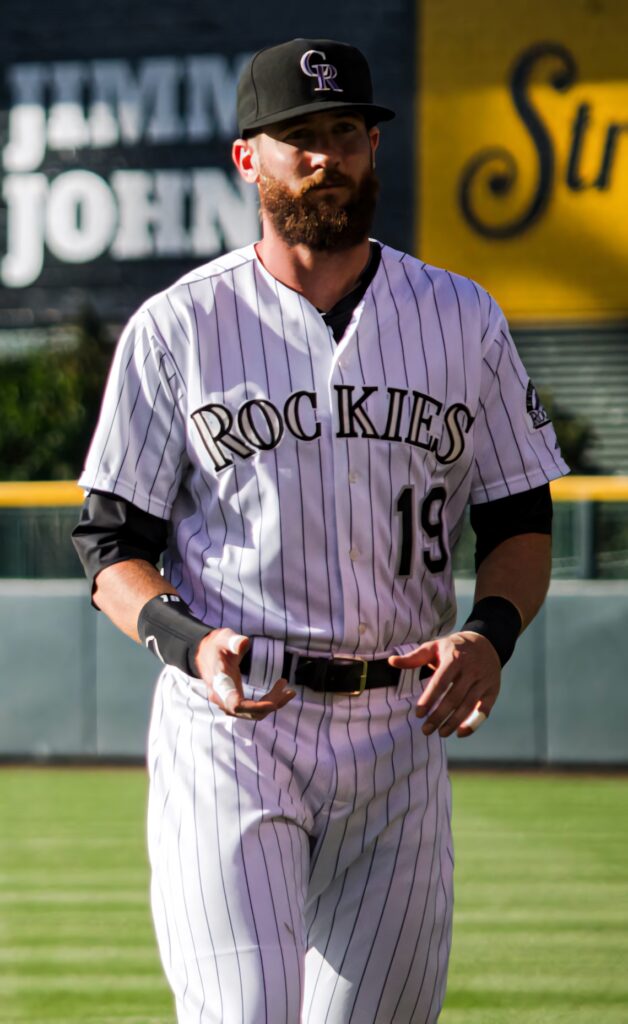 Charlie Blackmon of Colorado Rockies walking on sunny vibrant green baseball field in pinstriped uniform Wallpaper