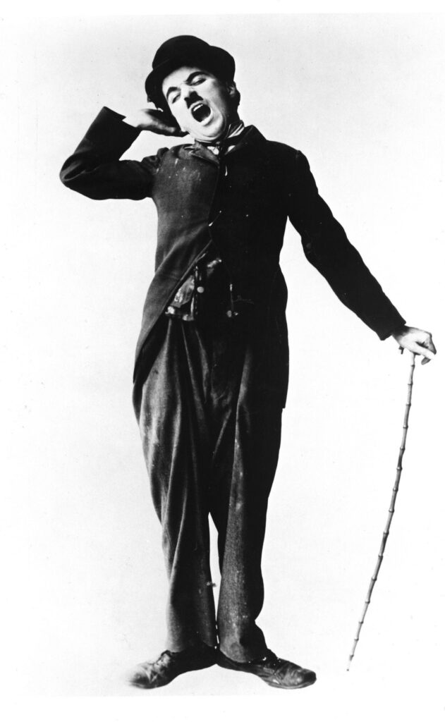 Charlie Chaplin iconic attire standing asleep with cane classic comedy wallpaper background