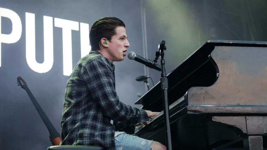Charlie Puth live on stage playing piano singing microphone energetic concert wallpaper background
