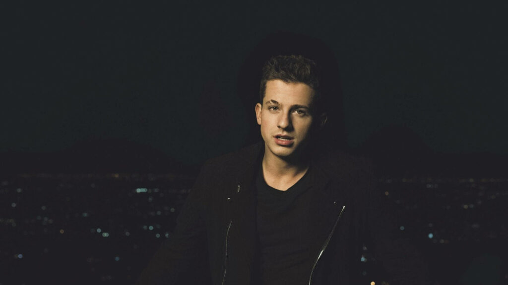 Charlie Puth standing at night with vibrant city lights creating moody atmospheric wallpaper