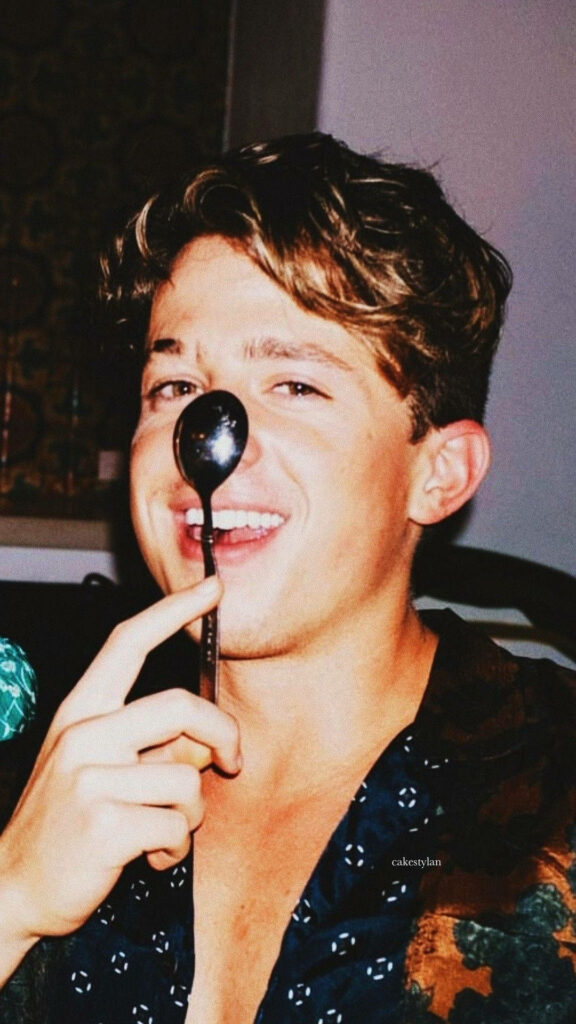 Charlie Puth balancing a spoon on his nose playful joyful moment vibrant wallpaper background