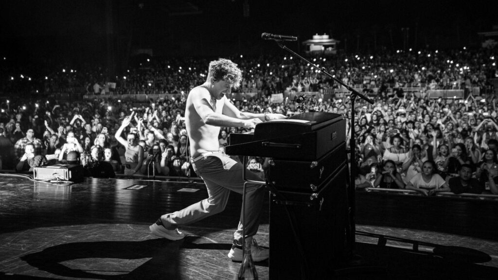 Charlie Puth shirtless playing piano passionately on stage with cheering crowd background wallpaper