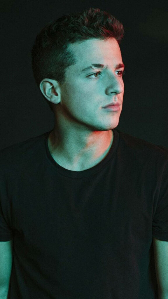 Charlie Puth side profile in black t-shirt with dramatic lighting on dark wallpaper background