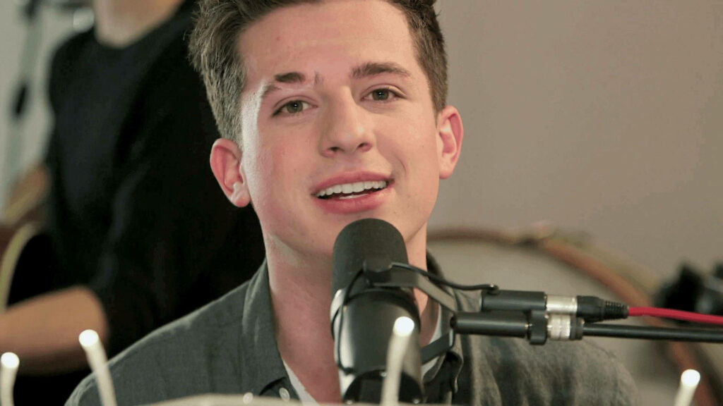 Charlie Puth singing passionately into microphone expressive performance vibrant wallpaper background