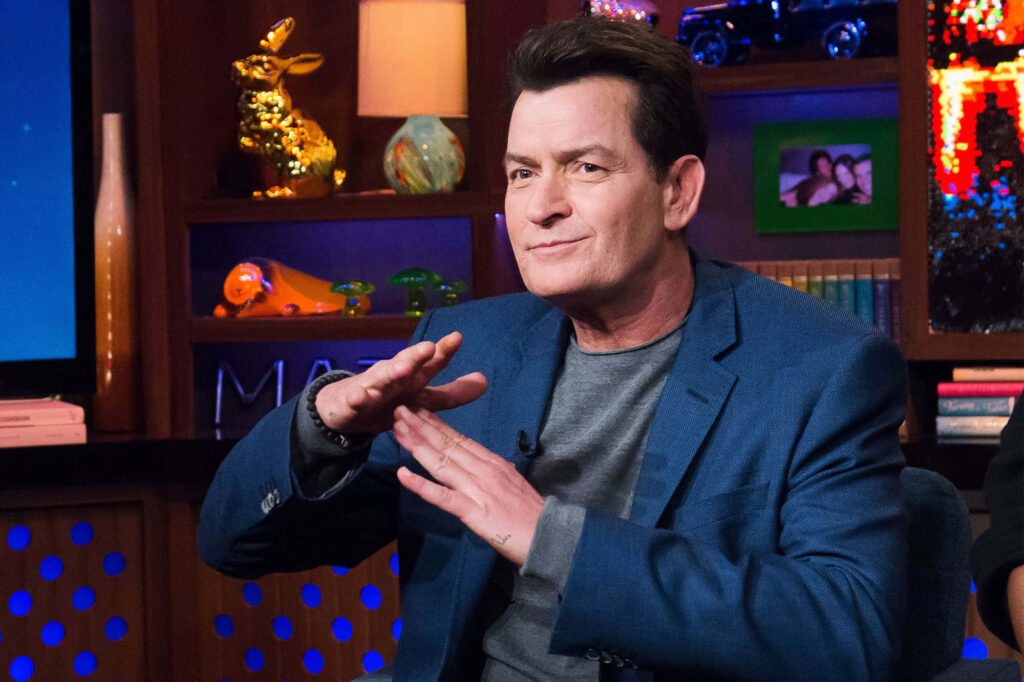 Charlie Sheen candid studio portrait wearing blue blazer gray shirt vibrant colorful background Wallpaper