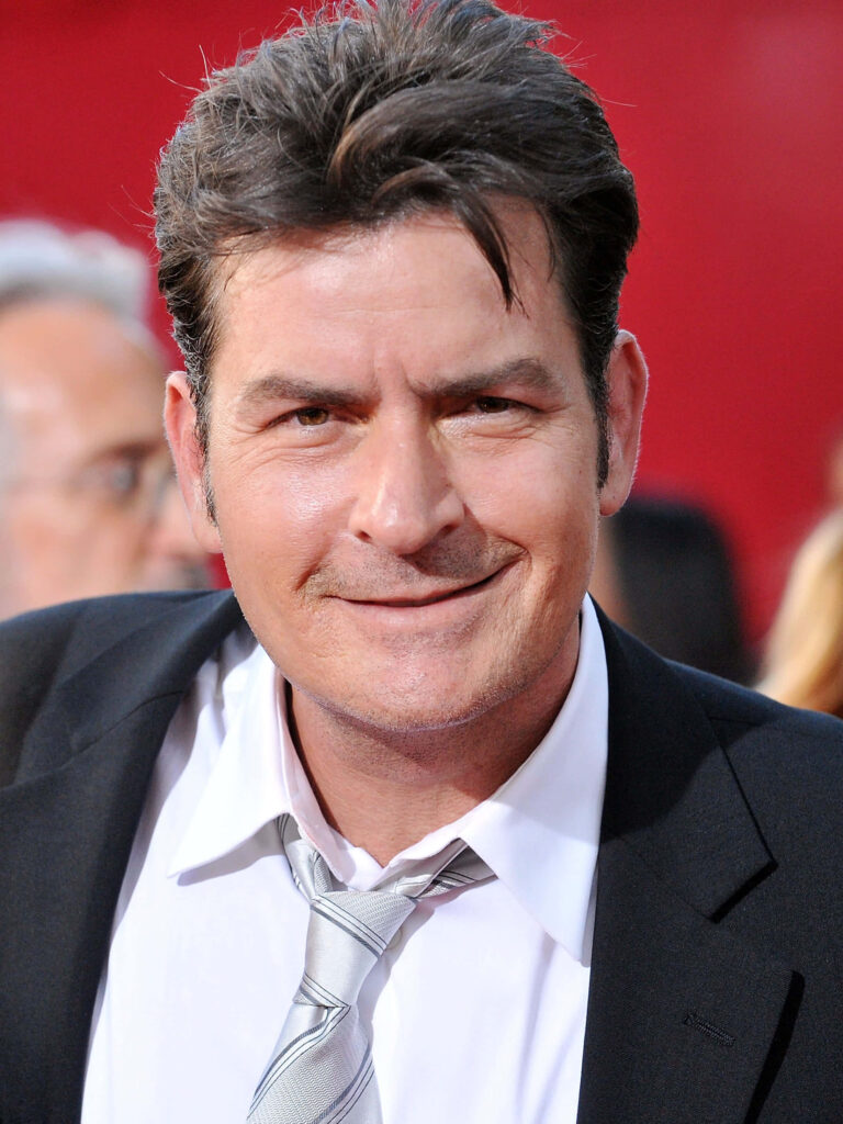 Charlie Sheen close-up portrait in black suit silver tie vibrant red background wallpaper