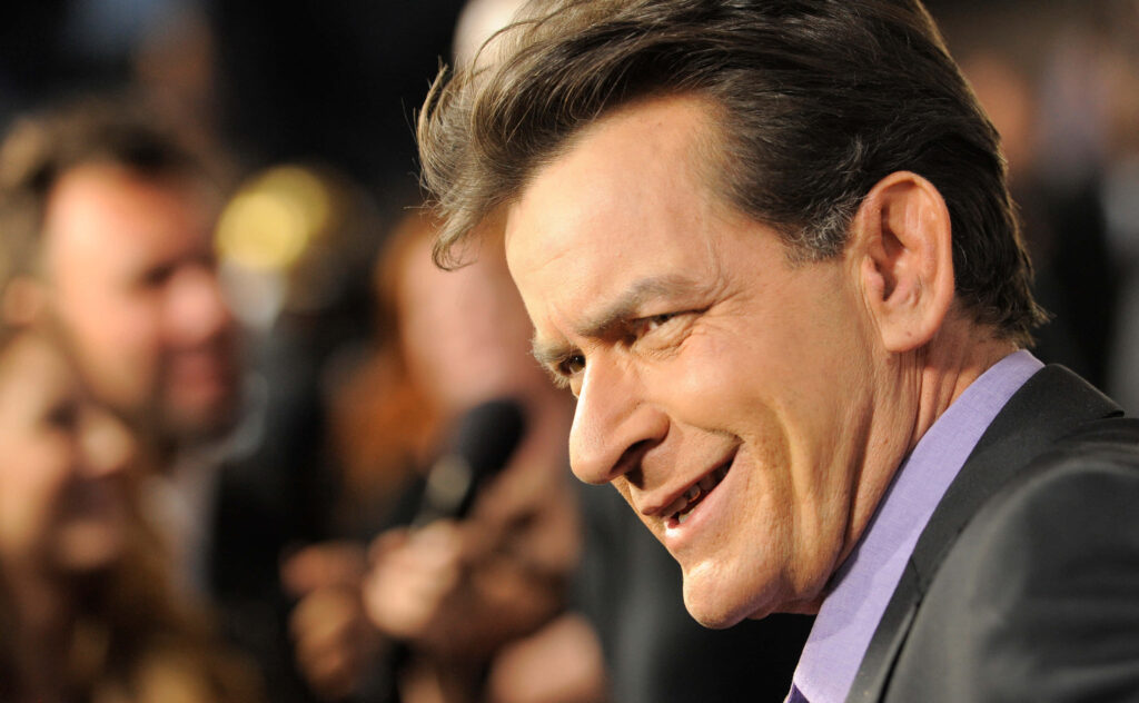 Charlie Sheen close-up portrait in suit and purple shirt with warm blurred background wallpaper