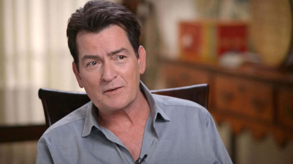 Charlie Sheen portrait wallpaper in light gray shirt with warm lighting and soft background