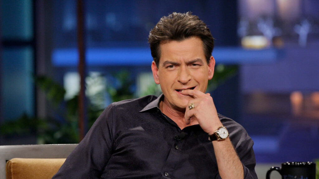 Charlie Sheen relaxed in studio setting with confident expression dark shirt soft blurred background Wallpaper