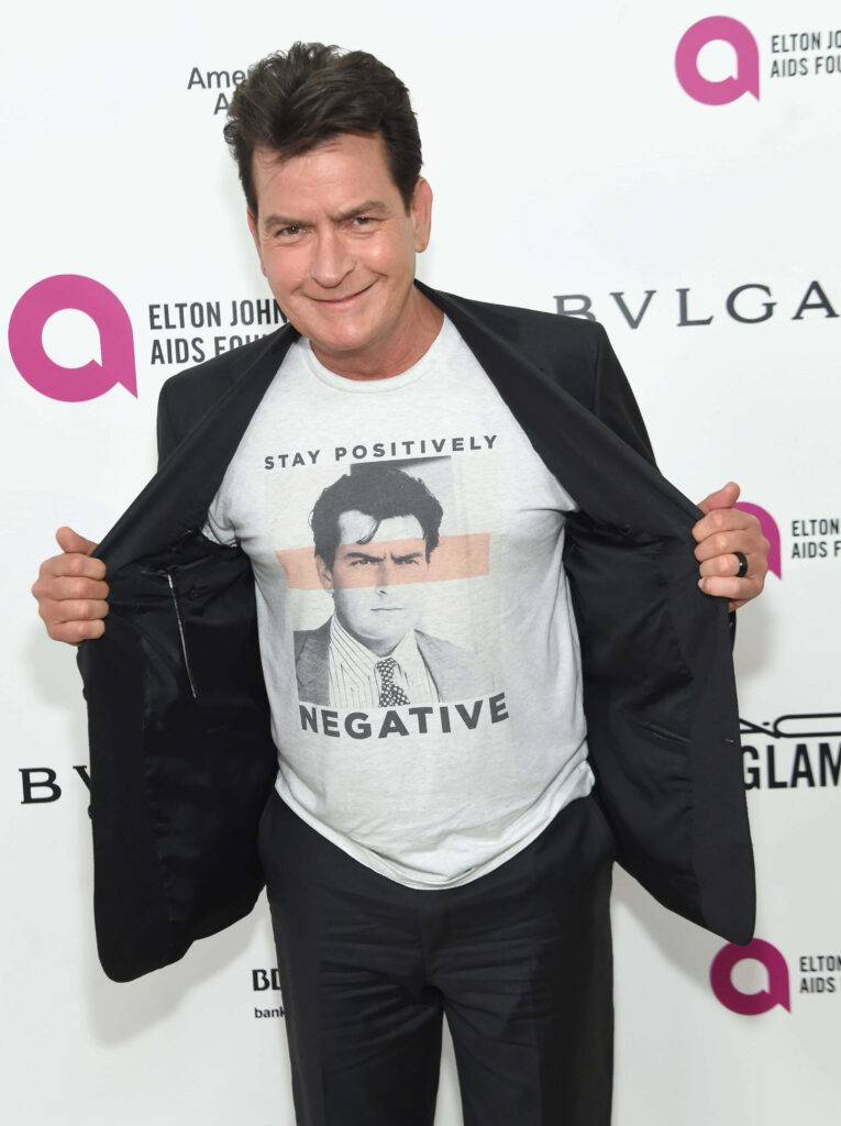 Charlie Sheen at formal event wearing black jacket and T-shirt with Stay Positively Negative design Wallpaper
