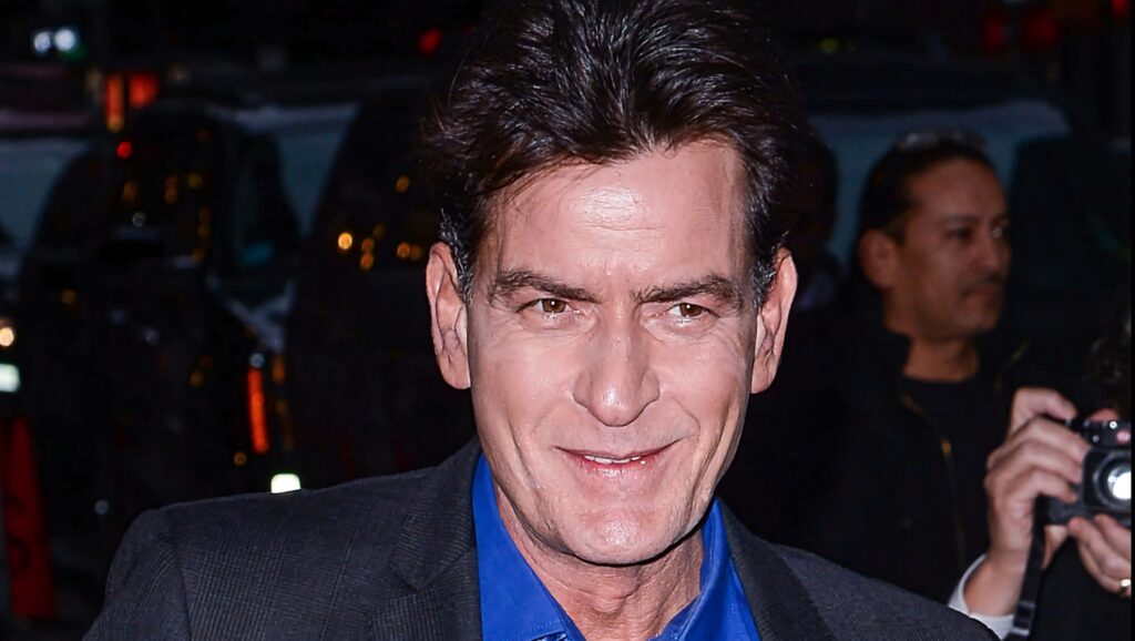 Charlie Sheen in blue shirt and blazer smiling candidly urban background natural light wallpaper