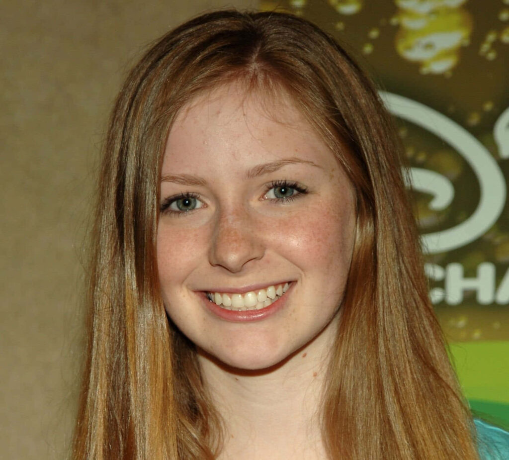 Charlotte Arnold smiling with auburn hair against earthy green tones warm friendly wallpaper background