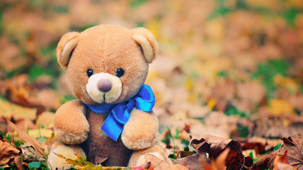 Fuzzy Companion Wrapped in Serene Blue: HD Wallpaper Featuring a Brown Teddy Bear with a Blue Ribbon