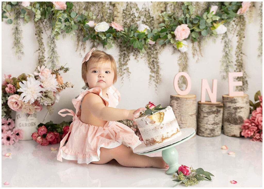 Charming Cake Smash Celebration: Adorable Toddler in Lush Garden Wallpaper