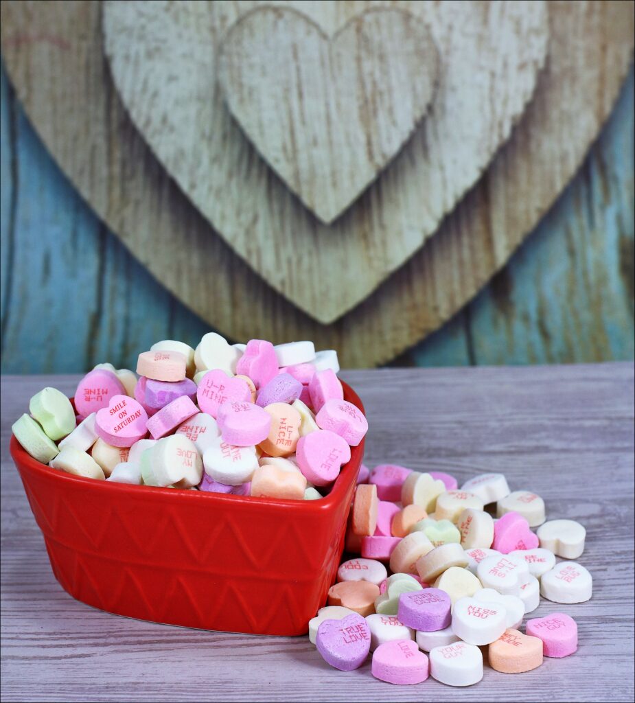 Charming Pastel Candy Hearts Wallpaper on Rustic Wooden Surface