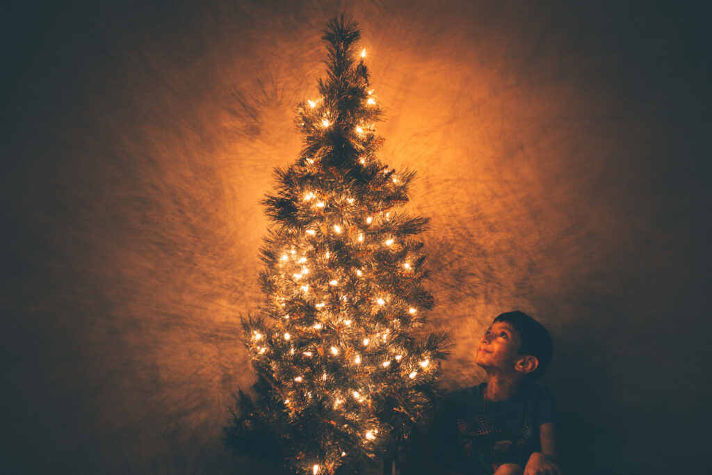 Child's Wonder at a Beautifully Lit Christmas Tree Wallpaper