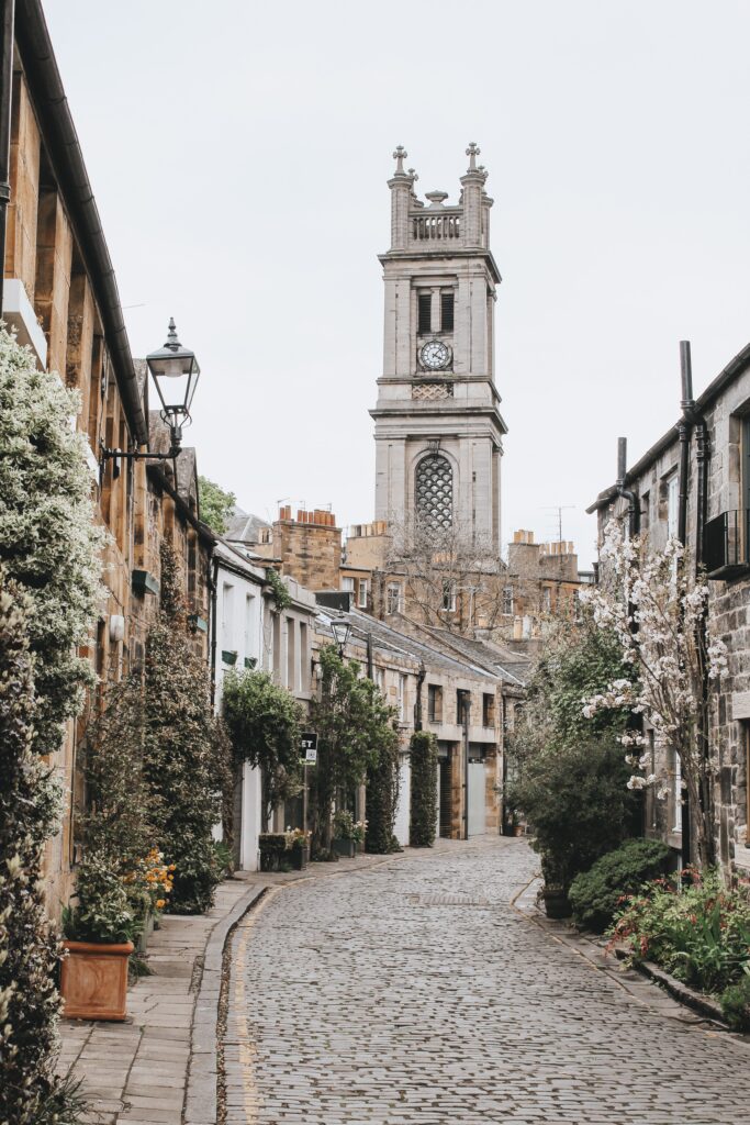 Charming Cobblestone Street Wallpaper with Historic Tower and Greenery