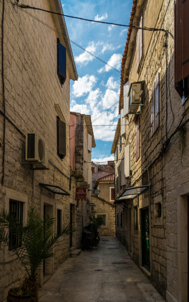 Charming narrow Croatian alley with rustic stone buildings colorful shutters and clear blue sky Wallpaper