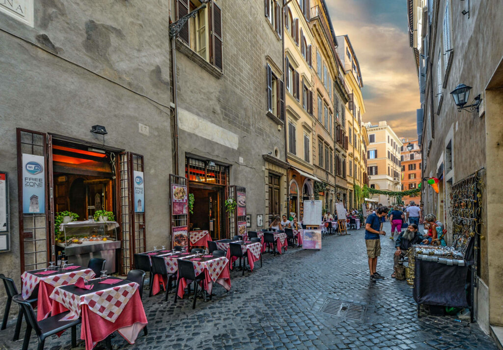 Charming European street café with pink white tables on cobblestone alley at sunset wallpaper