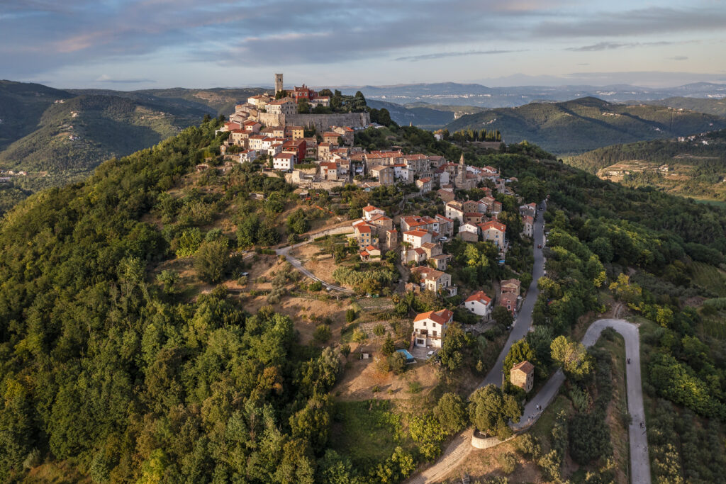 Charming Hillside Village Wallpaper Surrounded by Lush Greenery
