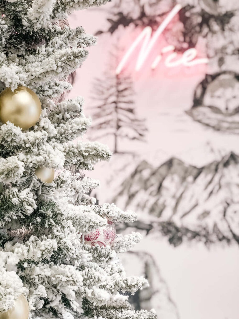 Charming Holiday Scene: Flocked Tree & Pink Neon 'Nice' Sign Wallpaper