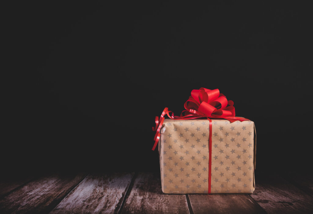 Vibrant Red Bow Gift Box Wallpaper on Rustic Wooden Surface