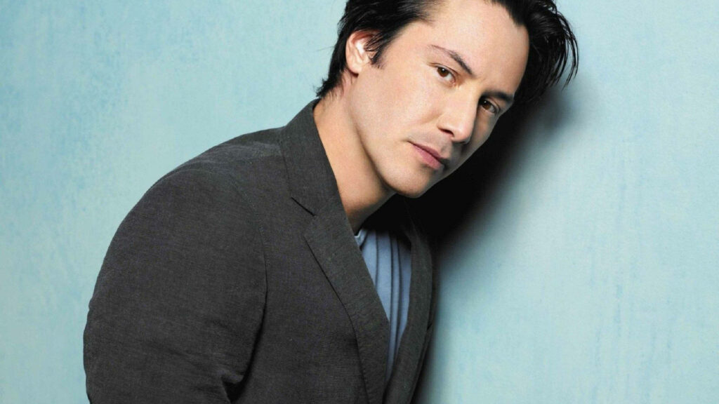 Youthful Keanu Reeves Wallpaper: Charm & Sophistication in Blue