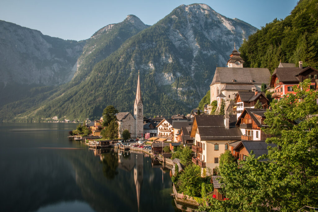 Lakeside village with charming houses church tower and green mountains reflected in calm water wallpaper