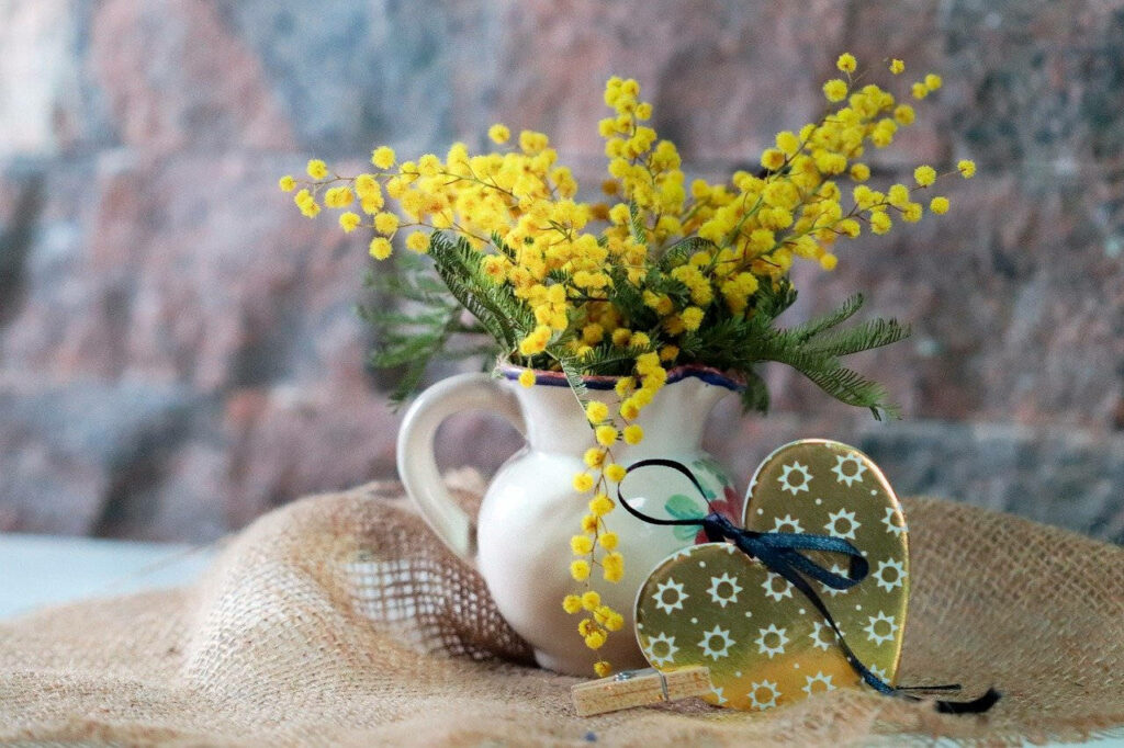 Charming Yellow Mimosa Flowers in White Pitcher on Rustic Burlap Wallpaper