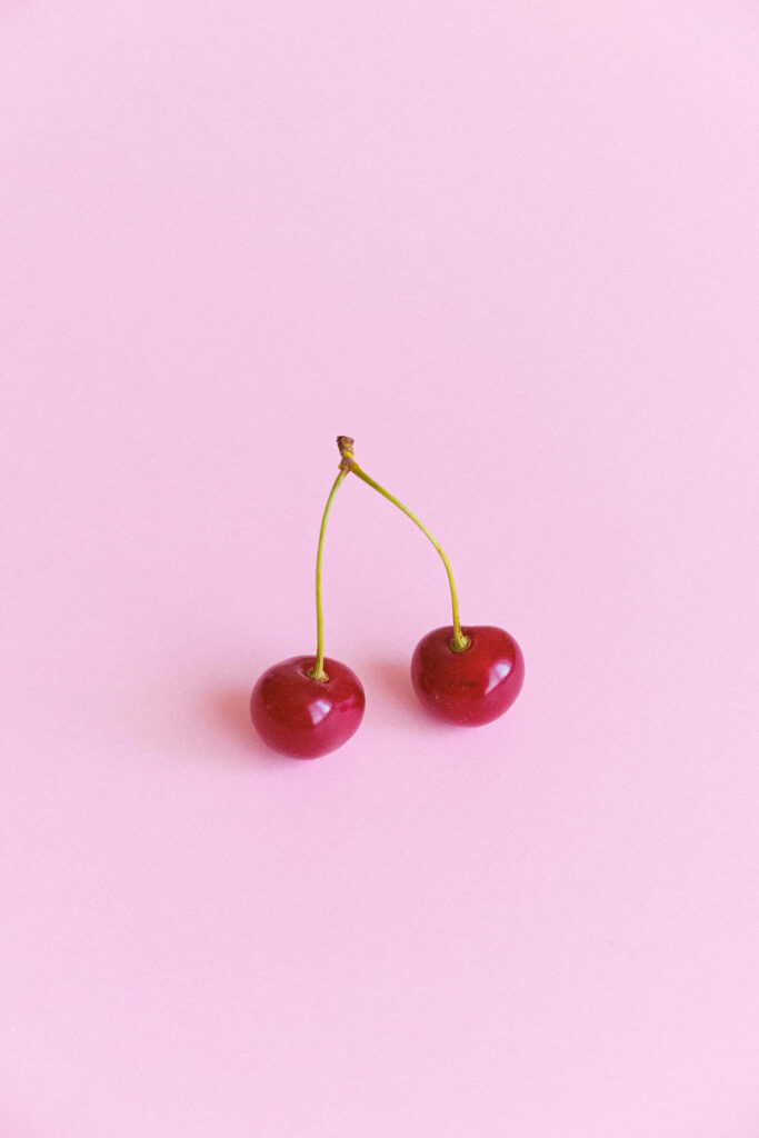 Charming Minimalist Wallpaper: Red Cherries on Soft Pink Background