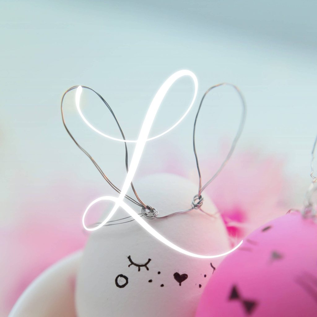 Cute white and pink eggs with wire rabbit ears and faces around a glowing script L wallpaper