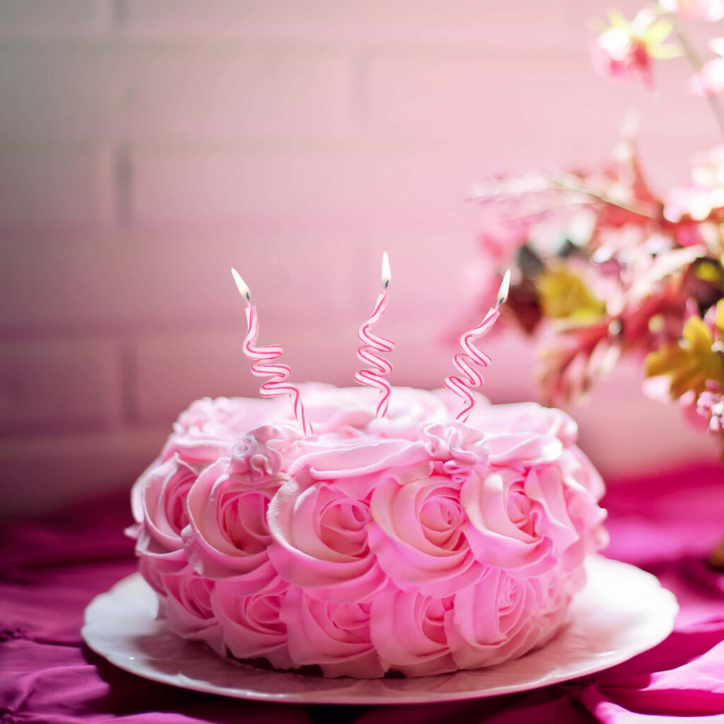 Charming Pink Cake with Rose Frosting & Candles in Soft Lighting Wallpaper