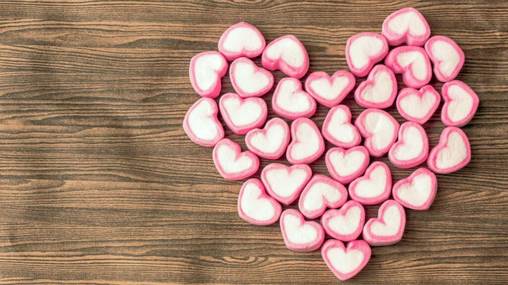 Charming Pink Heart Candy Wallpaper on Rustic Wooden Background