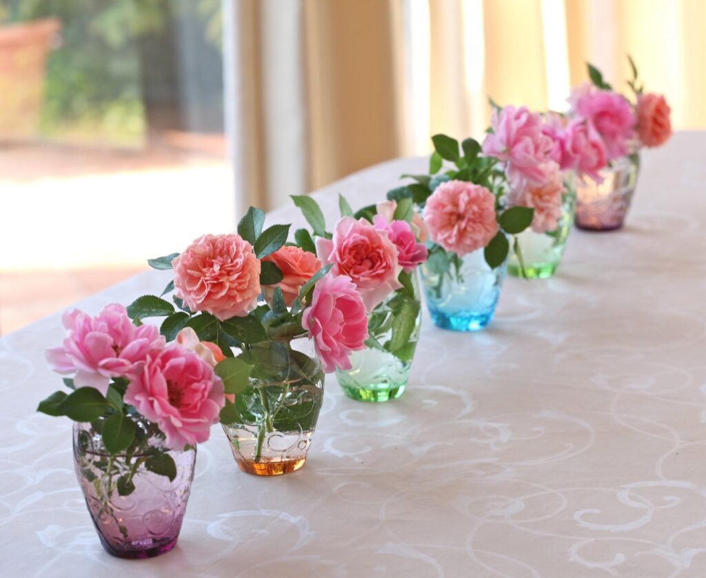 Charming Pink Roses in Colorful Vases on Elegant Tablecloth Background Wallpaper