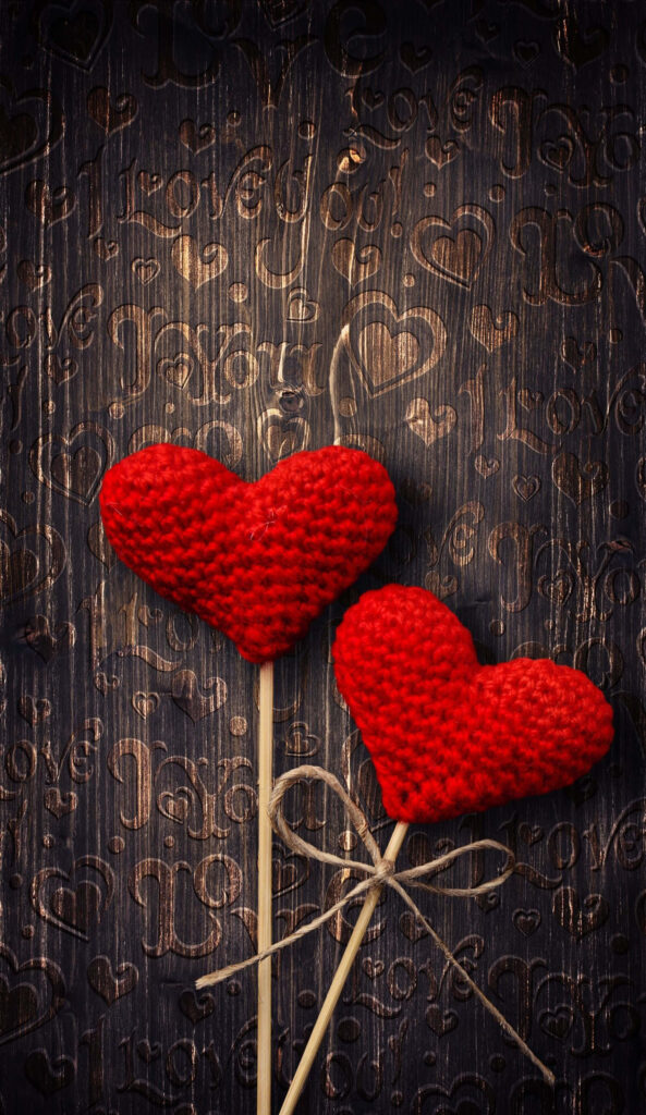 Charming Red Crocheted Hearts Wallpaper on Textured Dark Wood