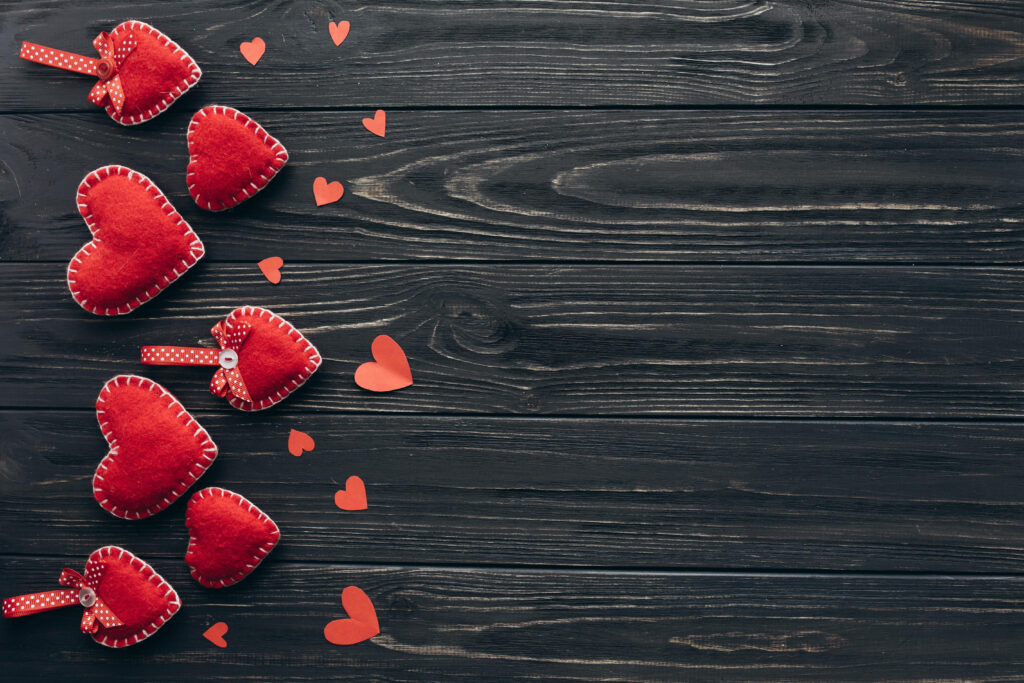 Charming Red Heart Ornaments Wallpaper on Rustic Wood Background