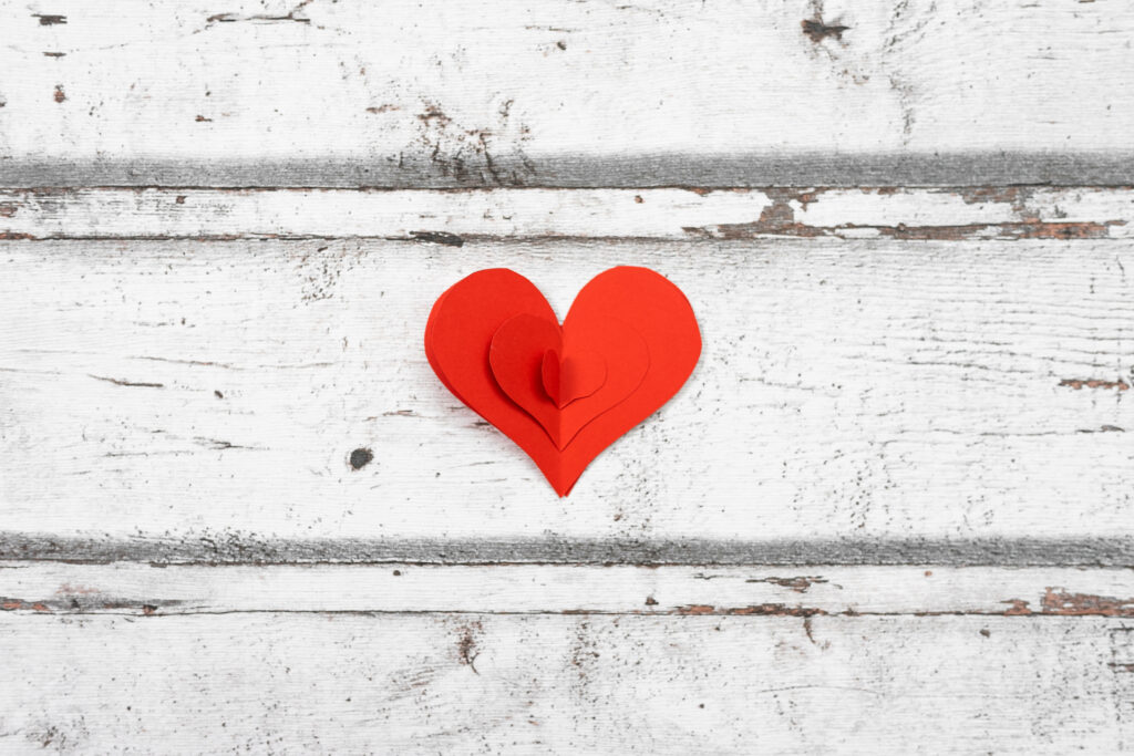 Charming Red Heart Paper Cutout Wallpaper on Rustic White Background
