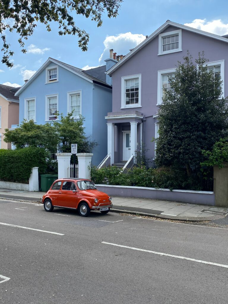Charming Retro Wallpaper: Classic Red Car & Pastel Buildings Background