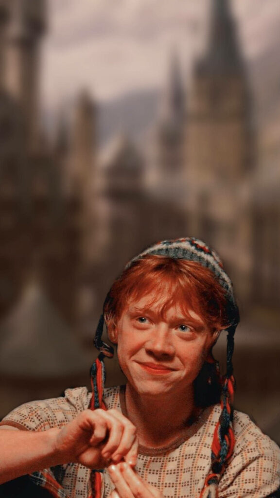 Charming Ron Weasley Wallpaper with Blurred Hogwarts Background