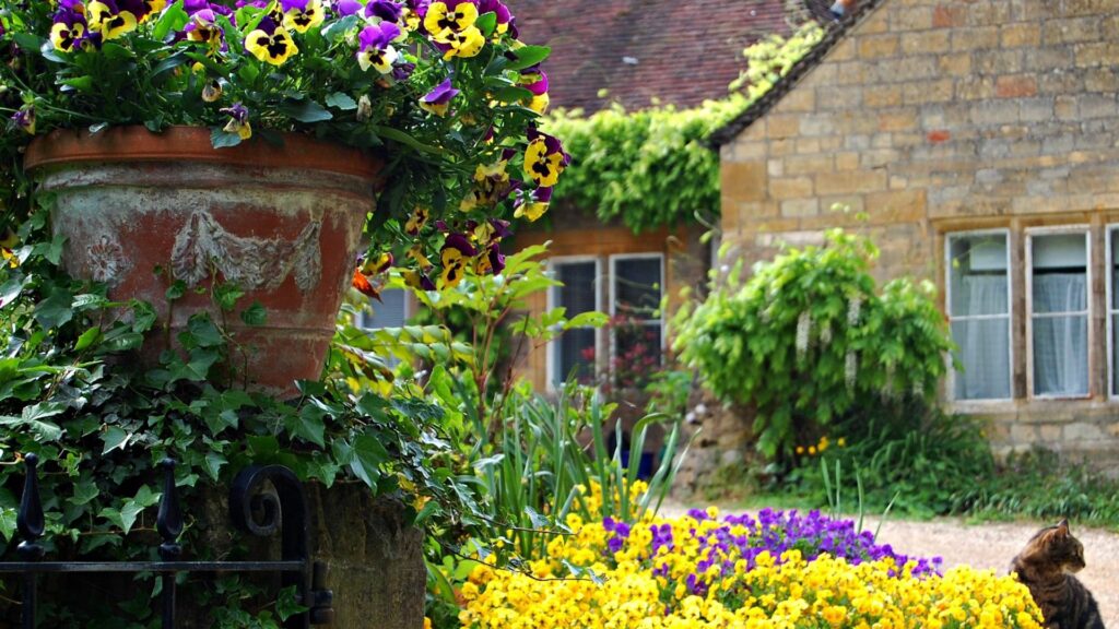 Rustic building with lush greenery colorful flowers and climbing ivy in serene garden wallpaper