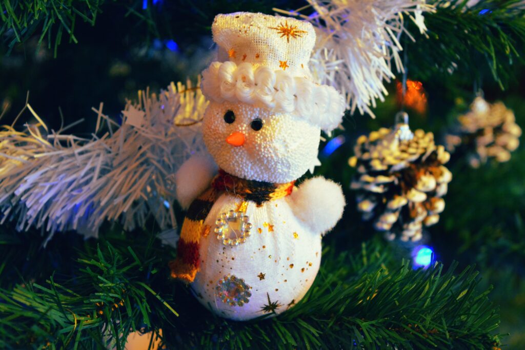 Charming Snowman Ornament Amidst Evergreen & Twinkling Christmas Decor Wallpaper