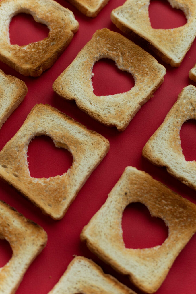 Charming Toasted Bread Wallpaper with Heart Cutouts on Red Background