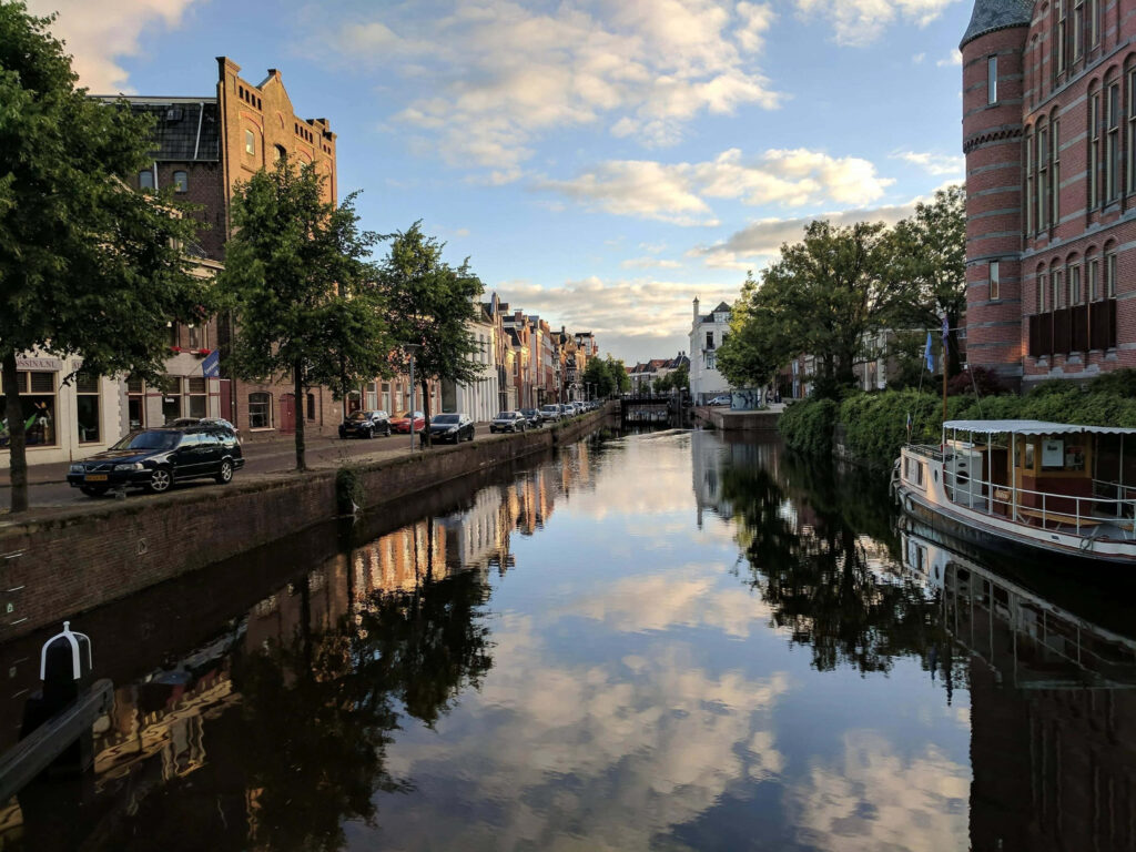 Charming Canal Reflection: Historic Buildings & Greenery Wallpaper
