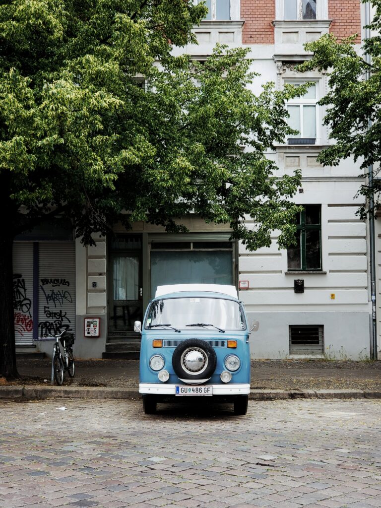 Charming Vintage Blue Van Wallpaper: Nostalgic Urban Scene